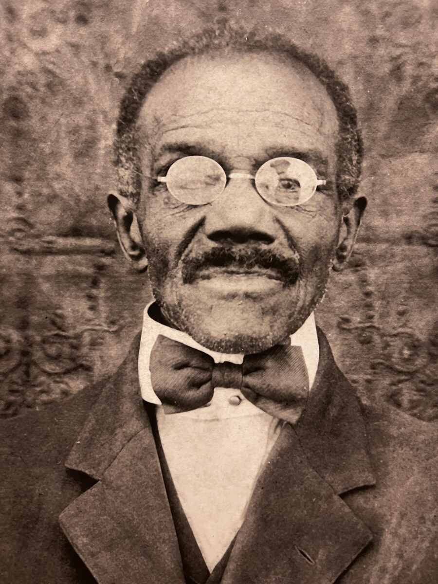 Man wearing a suite, with glasses and bow tie.